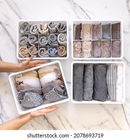 Woman hands placing wardrobe drawer organizers with full of folded underwears. Sock drawer with folded socks. Perfect and neatly setting of clothes. Linen drawer organization solution. Perfectionist.
