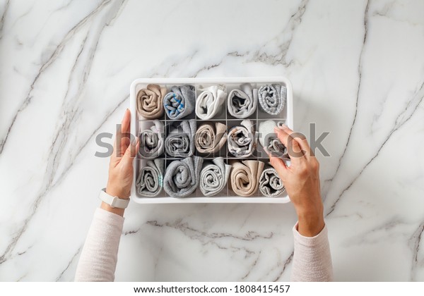 Woman hands placing wardrobe drawer\
organizers with full of folded underwears. Sock drawer with folded\
socks. Perfect and neatly setting of clothes. Linen drawer\
organization solution.\
Perfectionist.