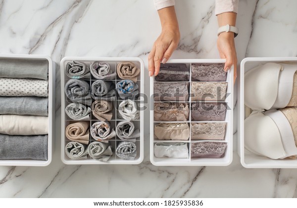 Woman hands placing wardrobe drawer\
organizers with full of folded underwears. Sock drawer with folded\
socks. Perfect and neatly setting of clothes. Linen drawer\
organization solution.\
Perfectionist.