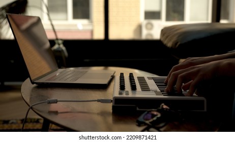 Woman Hands Playing On Small Midi Controller, Producer Of Music With Laptop On Table. Closeup Of Hands Playing On Keys, Home Studio With Professional Equipment. 