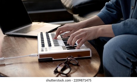 Woman Hands Playing On Small Midi Controller, Producer Of Music With Laptop On Table. Closeup Of Hands Playing On Keys, Home Studio With Professional Equipment. 