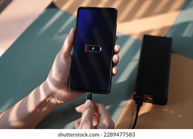 Woman hands plugging the charger into smart phone at the coffee shop - Shutterstock ID 2289477583