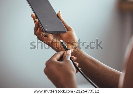 Woman hands plugging a charger in a smart phone. Woman using smartphone with powerbank. Young woman charging power to smart phone. Woman charging battery on mobile phone at home