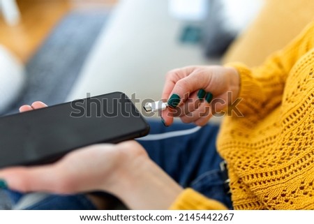 Woman hands plugging a charger in a smart phone. Woman using smartphone with powerbank, charging power to smart phone. Woman charging battery on mobile phone at home Foto stock © 