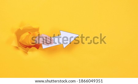 Woman hands pointing arrow on copyspace isolated through torn yellow wall orange background studio Copy space advertisement place for text image promotional content Advertising area workspace mock up