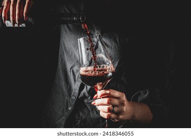 woman hands pouring red wine into a glass from a bottle on black background - Powered by Shutterstock