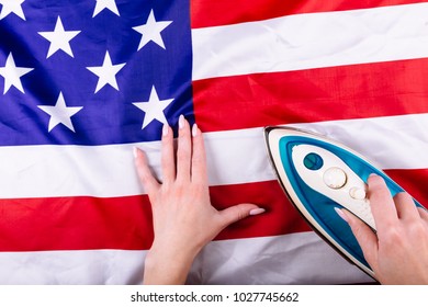Woman Hands Pressing American Flag With An Iron. Visual Concept Of Preparation For Independence Day. Fourth Of July Patriotic Consept.