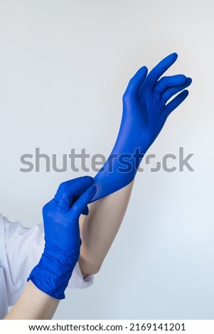 Woman hands putting on blue sterile protective gloves close up. Isolated hands on white background. Preparation for a surgery, manicure, pedicure.