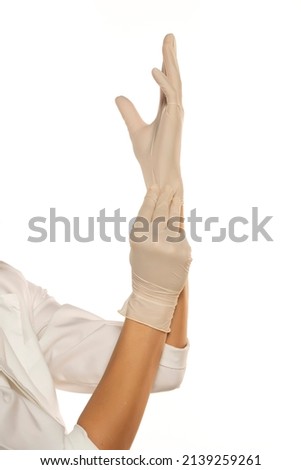Woman hands putting on a latex gloves on a white background