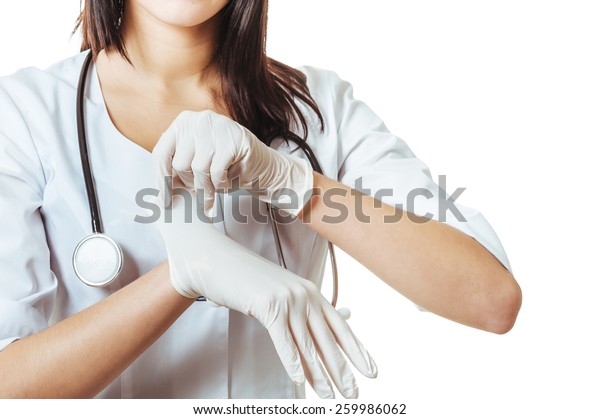 白い背景に女性の手がラテックスの手袋をはめる ラテックス手袋をはめたドクター服の女性 の写真素材 今すぐ編集