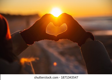 Woman hands in red winter gloves Heart symbol shaped Lifestyle, Winter Solstice and Feelings concept with sunset light nature on background - Shutterstock ID 1871343547