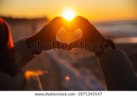 Woman hands in red winter gloves Heart symbol shaped Lifestyle, Winter Solstice and Feelings concept with sunset light nature on background
