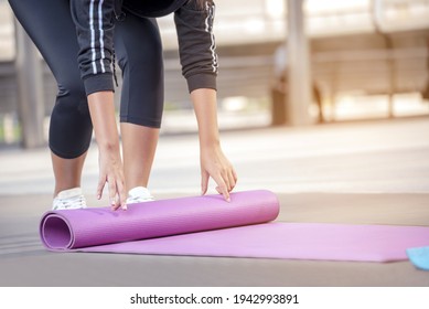 Woman Hands Rolled Up Yoga Mat Outdoor Workout. Close Up Hands Rolling Foam Yoga Gym Mat Outside Morning Exercise. Woman Stretching Workout Sportive Healthy Lifestyle On Street City Town Park Concept