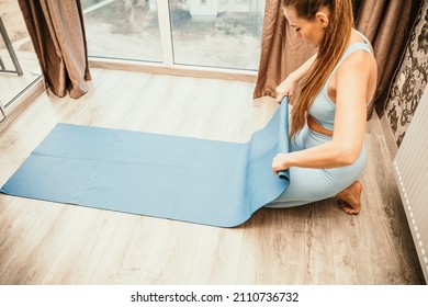 Woman Hands Rolled Up Yoga Mat On Gym Floor In Yoga Fitness Training Room. Home Workout Woman Close Up Hands Rolling Foam Yoga Gym Mat. Woman Barefoot Home Workout Sportive Healthy Lifestyle Concept