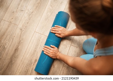 Woman Hands Rolled Up Yoga Mat On Gym Floor In Yoga Fitness Training Room. Home Workout Woman Close Up Hands Rolling Foam Yoga Gym Mat. Woman Barefoot Home Workout Sportive Healthy Lifestyle Concept