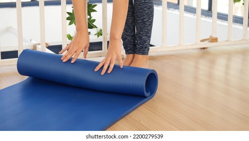 Woman Hands Rolled Up Yoga Mat On Gym Floor In Yoga Fitness Training Room. Home Workout Woman Close Up Hands Rolling Foam Yoga Gym Mat. Woman Barefoot Home Workout Sportive Healthy Lifestyle Concept