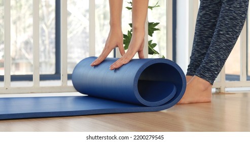 Woman Hands Rolled Up Yoga Mat On Gym Floor In Yoga Fitness Training Room. Home Workout Woman Close Up Hands Rolling Foam Yoga Gym Mat. Woman Barefoot Home Workout Sportive Healthy Lifestyle Concept