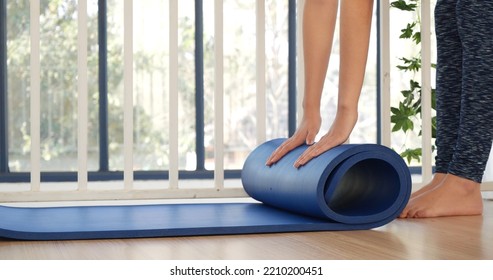 Woman Hands Rolled Up Yoga Mat On Gym Floor In Yoga Fitness Training Room. Home Workout Woman Close Up Hands Rolling Foam Yoga Gym Mat. Woman Barefoot Home Workout Sportive Healthy Lifestyle Concept