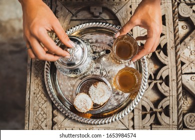 Woman hands serving traditional moroccan mint tea ceremony with cookies and vintage silver teapot. Hospitality and service in Morocco, Marrakech. - Powered by Shutterstock