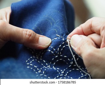 Woman hands sewing stitch blue fabric. Traditional Japanese sewing pattern call "SASHIKO". Traditional Japanese embroidery, learning ,teaching ,how to do,hand work, Japan craft,hobby concept.