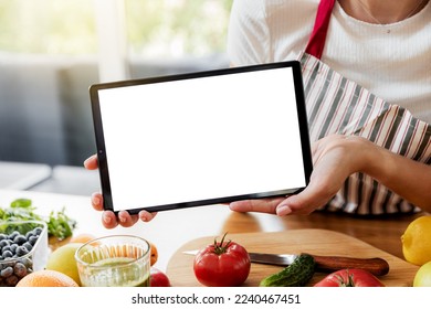 Woman hands showing digital tablet white empty blank screen mockup at kitchen. Chef using pc, present online grocery food shopping on computer. Delivery app ads concept, cook book or diet plan recipes - Powered by Shutterstock