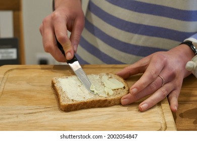 Woman hands spread bread with butter. High quality photo - Shutterstock ID 2002054847