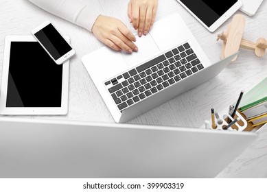 Woman hands at table with computer, tablet, smart phone and other things, top view