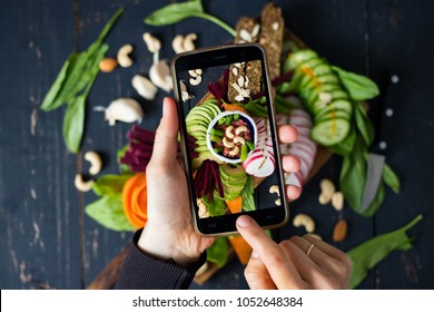 Woman hands takes food photo of mixed healthy buddha bowl on wooden board with vegetables and dip cashew sauce. Makes food photography for social networks with phone. Raw, vegan, vegetarian food - Powered by Shutterstock