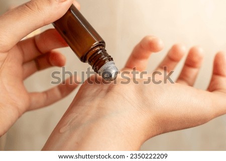 woman hands testing a roll on with essential oil , applying liquid on the wrist, soft focus close up