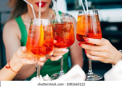 Woman hands toasting with aperol spritz cocktails