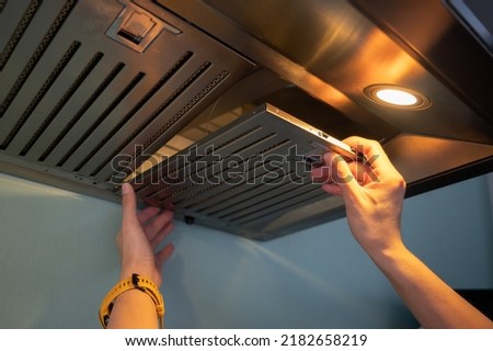 Woman hands trying to removing a filters from cooker hood for cleaning it. Clean your filters every two to three months, depending on your cooking habits. Foto d'archivio © 