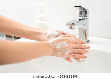 Woman hands are turning on the faucet at home and washing hands with clean water and soap for good hygiene. - Powered by Shutterstock