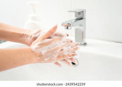 Woman hands are turning on the faucet at home and washing hands with clean water and soap for good hygiene. - Powered by Shutterstock