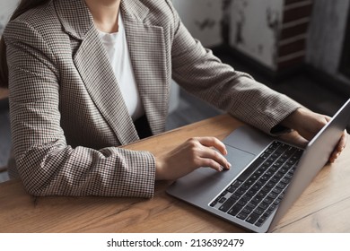 Woman hands typing on touchpad computer, working remote online. Faceless business woman working on laptop at workplace in a trendy modern office with the table