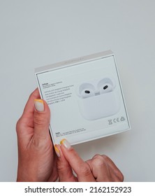 Woman Hands Unpacking New Model AirPods 3 2021 On White Background. The Box From Previous Release Of Apple Earphones Lying Down On Back Stage. Copy Space.