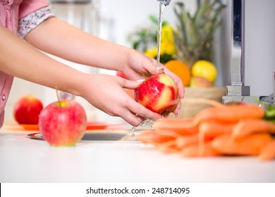 Woman hands washing tasty apple under the tap