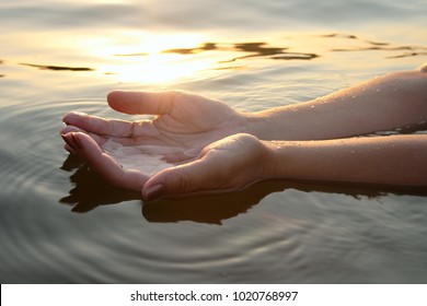 Woman hands in water inviting you over sunset golden rays. - Powered by Shutterstock