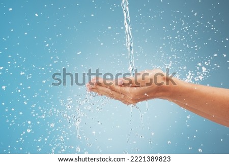 Woman, hands and water splash on blue background in studio for healthcare, cleaning and washing hands. Zoom, model and pouring fresh faucet liquid in earth sustainability, conservation and protection