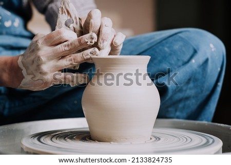 Woman hands working on pottery wheel and making a pot.