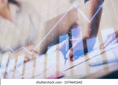A woman hands writing information about stock market in notepad. Forex chart holograms in front. Concept of research. Multi exposure - Shutterstock ID 1574641642
