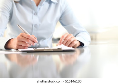 woman hands writing on clipboard with a pen, isolated on desk - Powered by Shutterstock