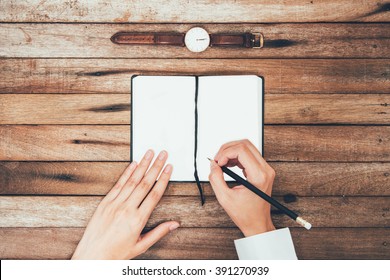 Woman Hands Writting Down On The Book Top View On Wooden Table Top View With Copy Space, On Vintage Background.