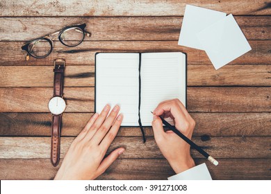 Woman Hands Writting Down On The Book Top View On Wooden Table Top View With Copy Space, On Vintage Background.