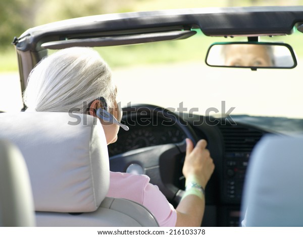 Woman with\
hands-free device in car, rear\
view