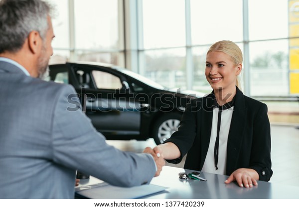 woman handshake\
with sell agent in car\
showroom