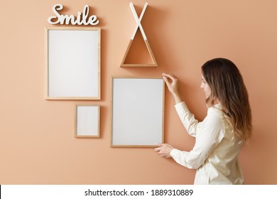 Woman Hanging Blank Photo Frames On Wall