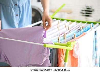 Woman hanging clean clothes on dryer in laundry room, closeup