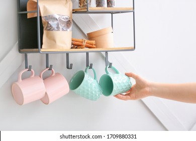 Woman hanging cup on shelf with kitchenware - Shutterstock ID 1709880331