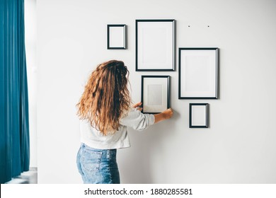 Woman hanging a frame on a wall.