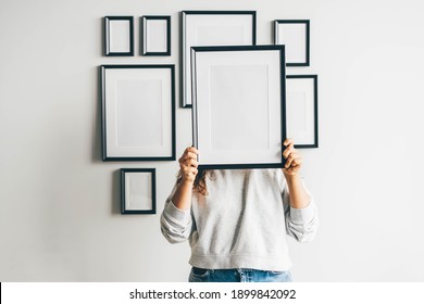 Woman Hanging A Frame On A Wall.